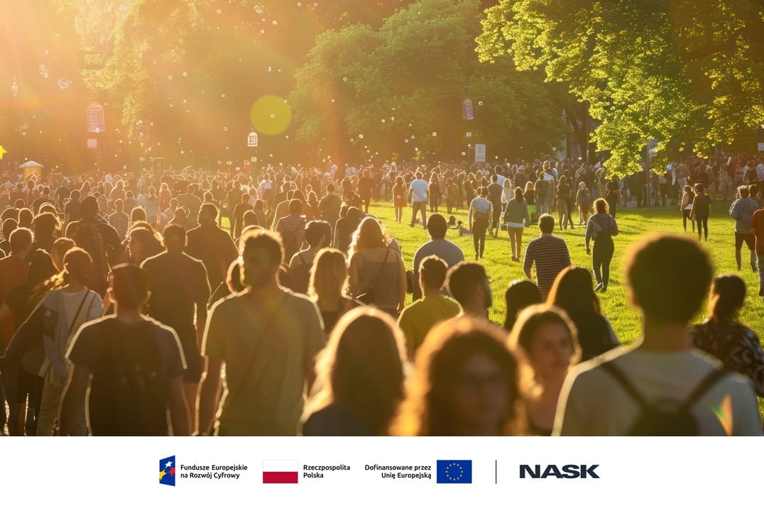 Tłum ludzi spaceruje po parku w ciepłym świetle zachodzącego słońca. Promienie słoneczne przenikają przez drzewa, tworząc złotą poświatę, a w powietrzu unoszą się bańki mydlane.