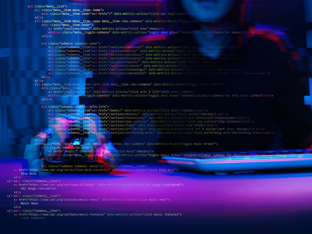 Zdjęcie przedstawia osobę siedzącą przy biurku, przed laptopem, z kodem HTML nałożonym w formie przezroczystej warstwy na cały obraz. Tło ma ciemne, niebiesko-fioletowe odcienie z lekkim efektem zakłóceń cyfrowych, a na pierwszym planie widoczne są kolorowe linie kodu zawierające struktury list i odnośniki.