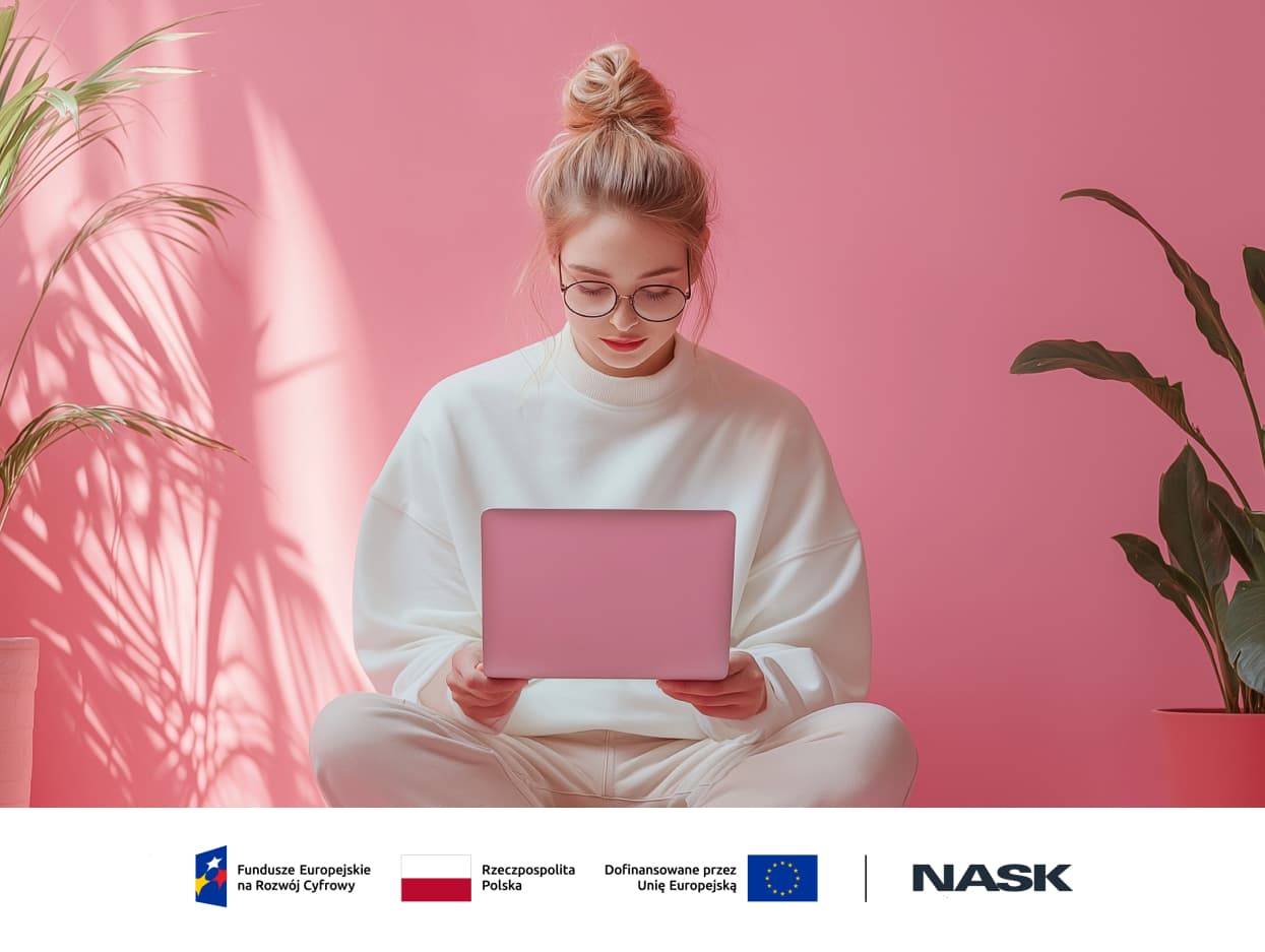 Zdjęcie kobiety, siedzącej  ze skrzyżowanymi nogami na tle różowej ściany z różowym tabletem.