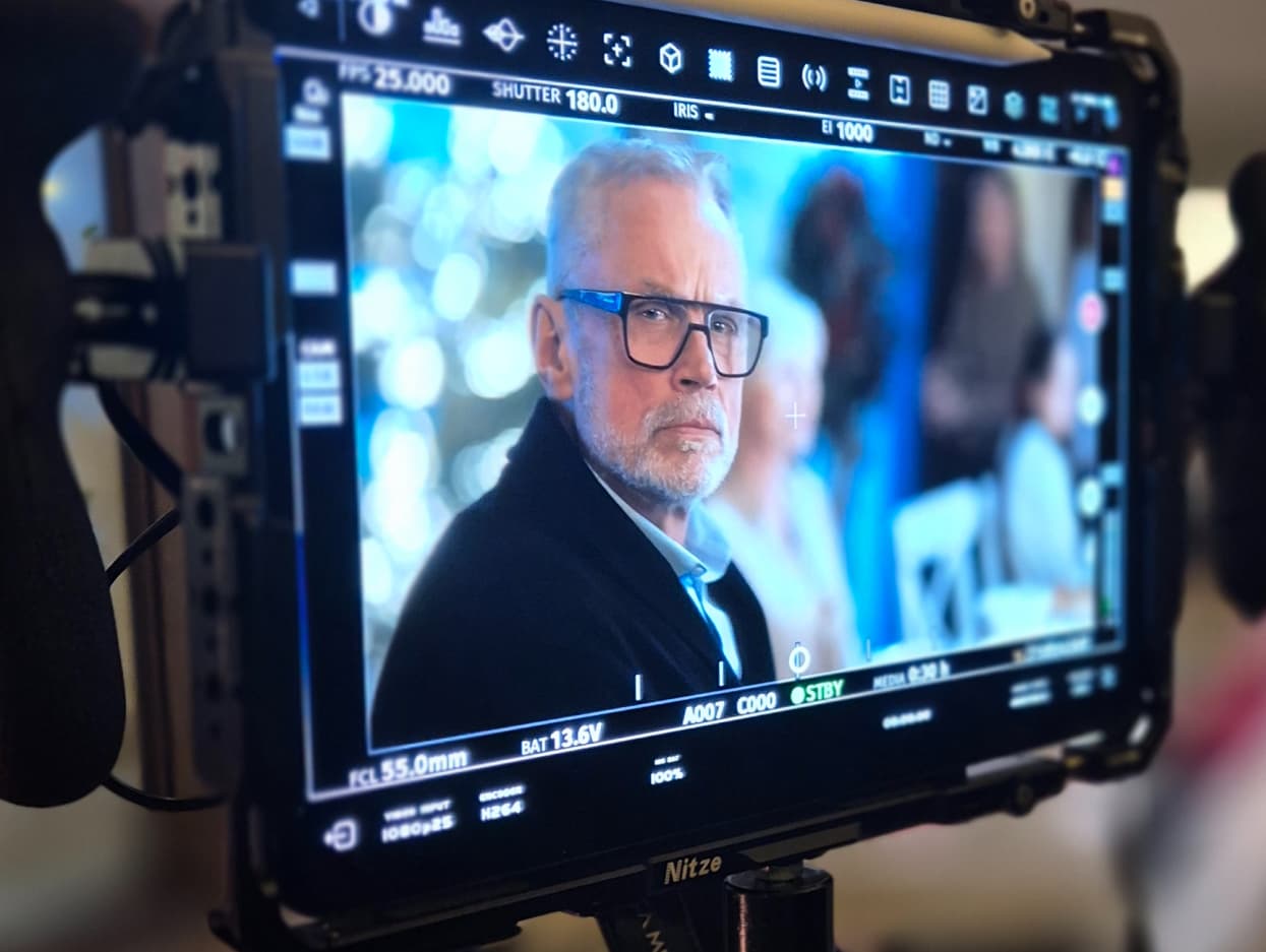 Ujęcie z podglądu na kamerze z planu zdjęciowego. Widać na nim aktora - starszego mężczyznę. 