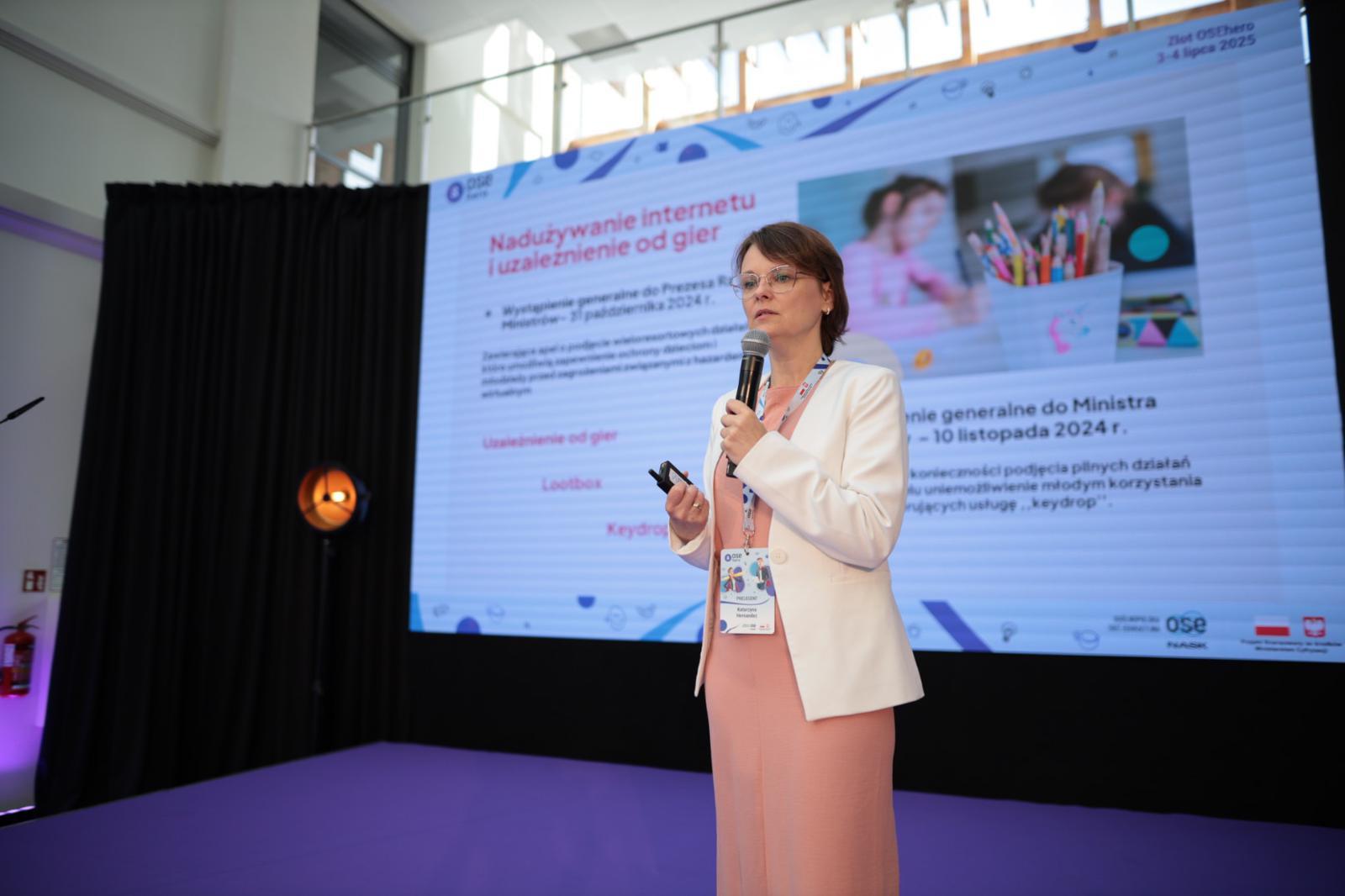 Uczestniczka Zlotu na scenie, w tle slajd prezentacji o nadużywaniu internetu i uzależnieniu od gier